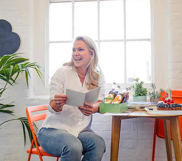 A smiling woman sitting at a table reading a booklet