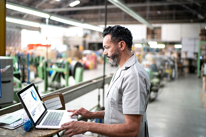 A Man working on a laptop in a factory setting