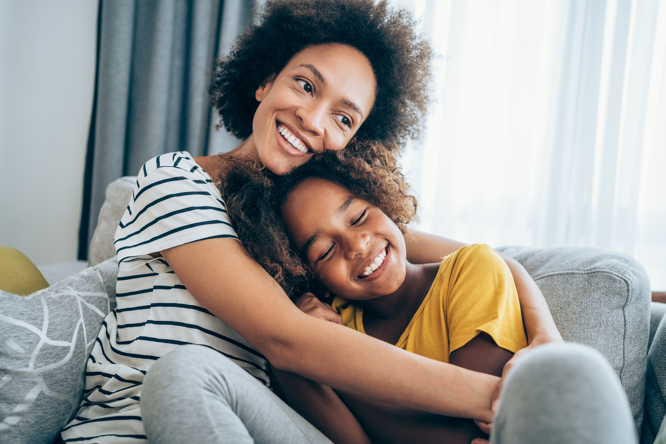 a mother and daughter cuddling together on a sofa