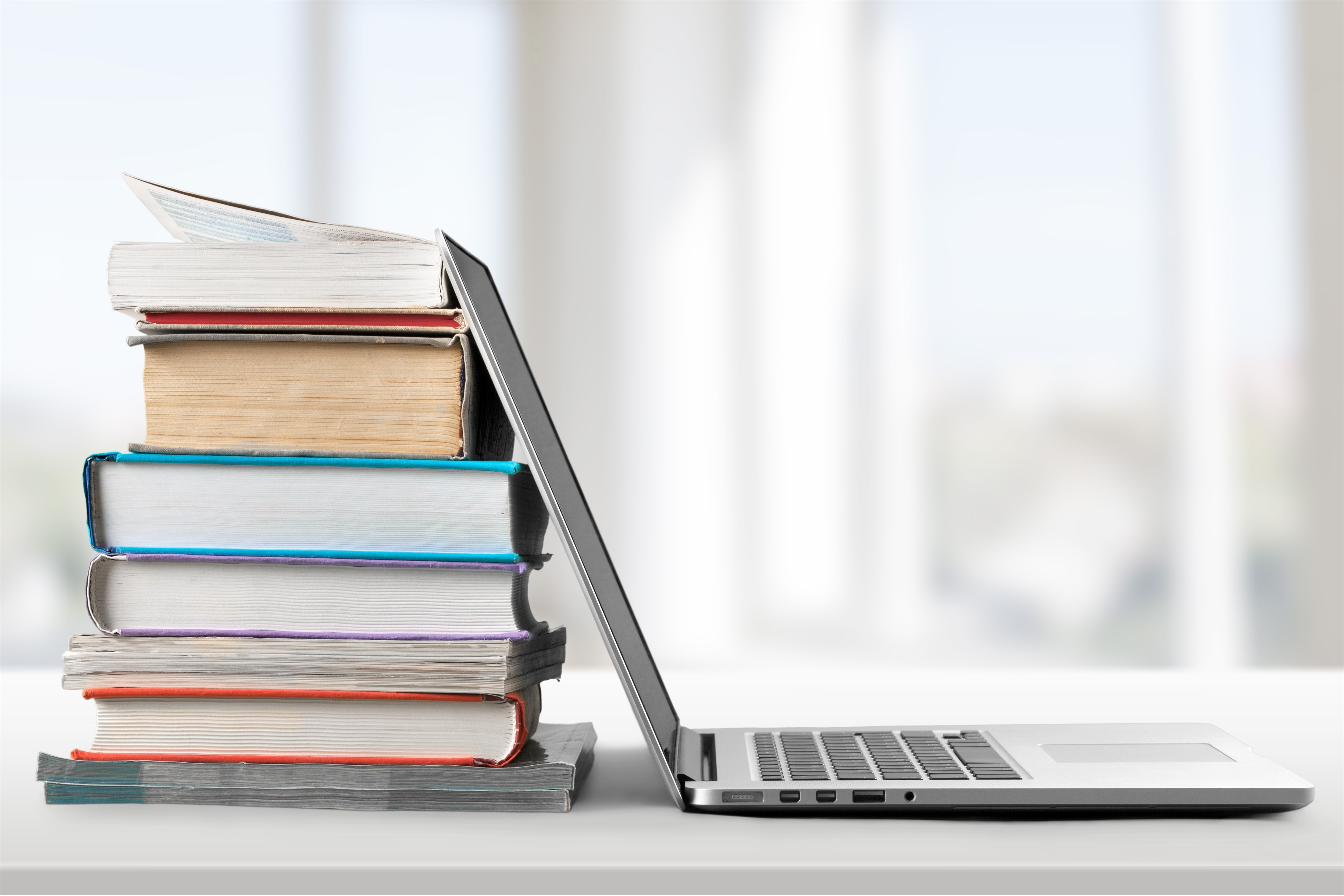 A laptop leaning against a stack of books