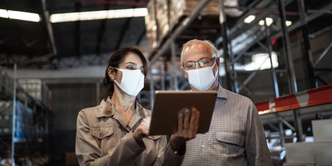 Joanne and Jeff reviewing safety protocol on a tablet on the manufacturing floor