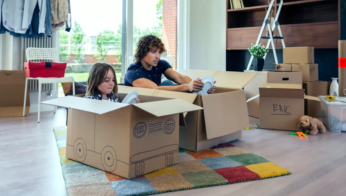 An adult and a child playing pretend in cardboard boxes