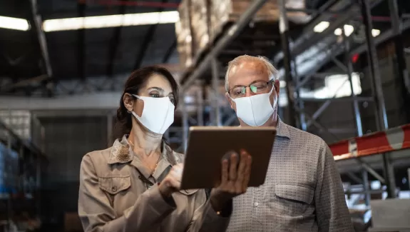 Joanne and Jeff reviewing safety protocol on a tablet on the manufacturing floor