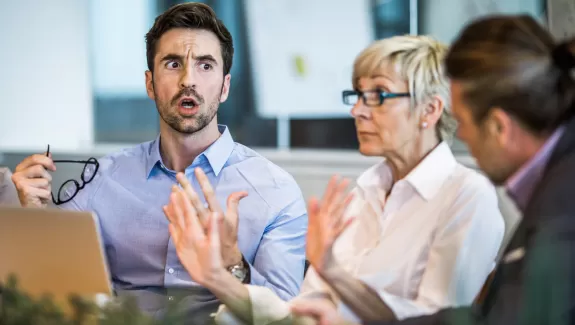 Three adults talking around a table in a work environment